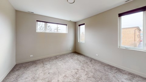 Empty room with carpeted floor and two windows.