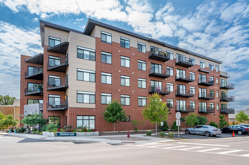 A large apartment building with balconies and a street in front.