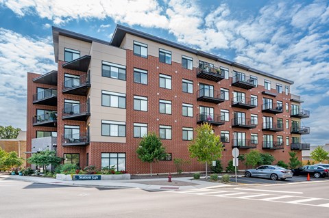 A large apartment building with balconies and a street in front.