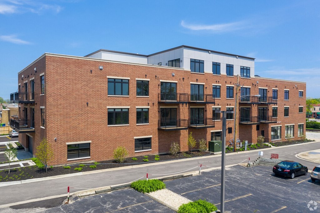 a red brick building with balconies and a parking lot  at Highwood 246, Highwood