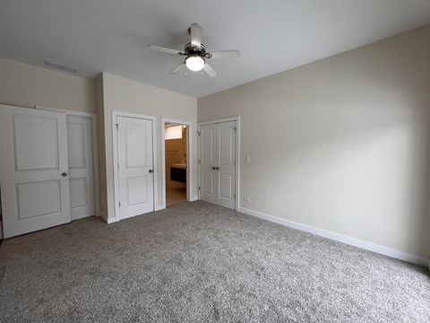 an empty living room with white doors and a ceiling fan