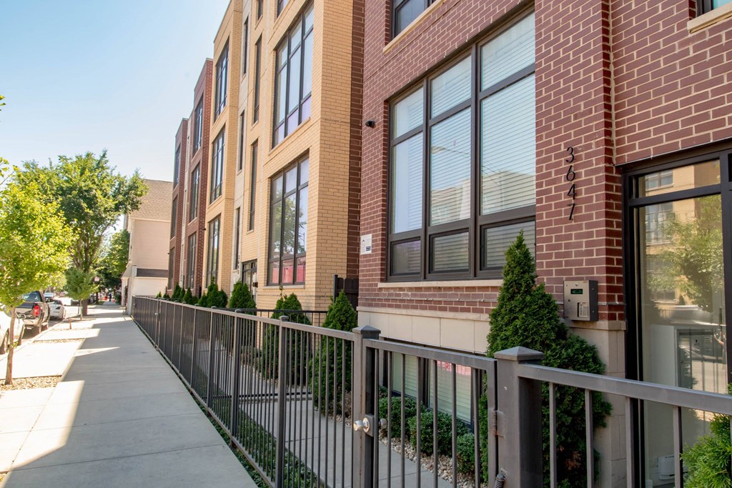 a sidewalk in front of a brick building with a fence at Montrose 3634, Chicago Illinois