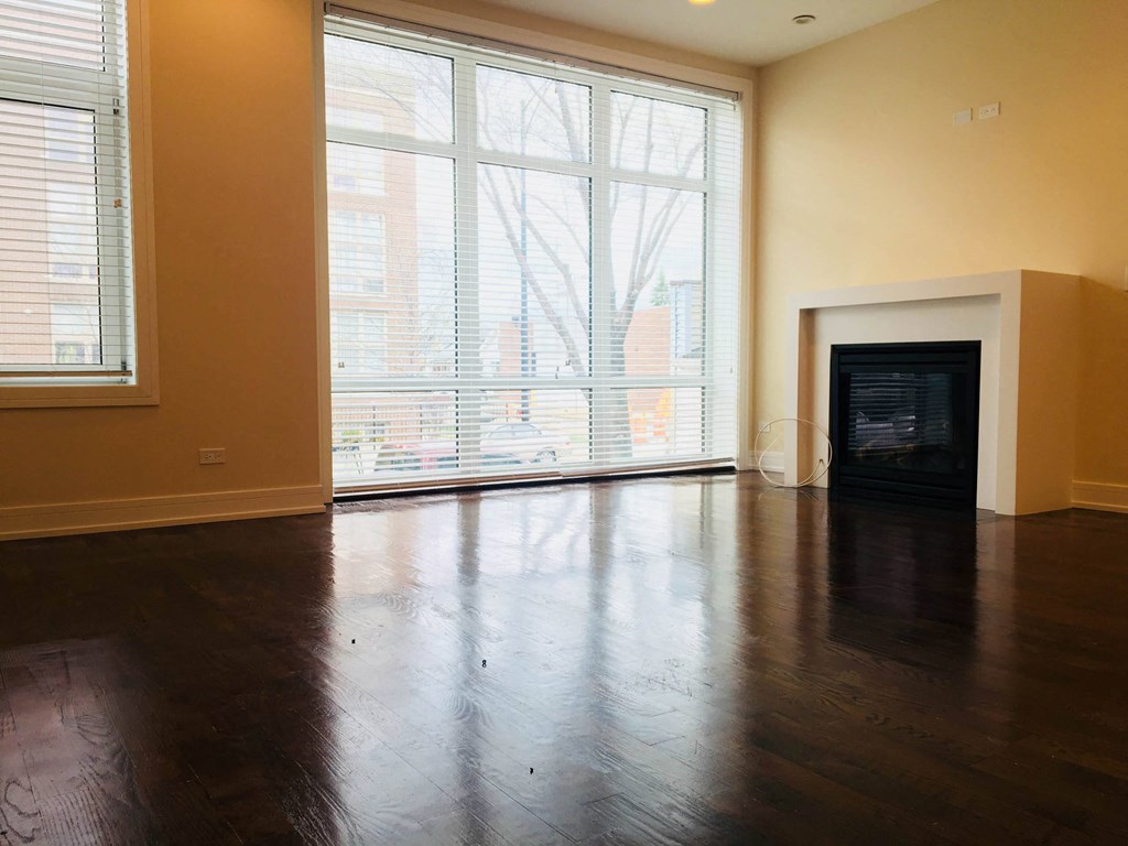 an empty living room with a large window and wood floors at Montrose 3634, Chicago Illinois