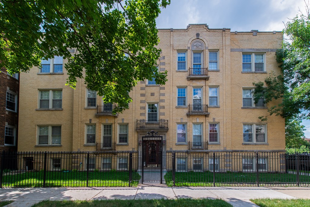a large brick building with a black fence in front of it at Christiana 4954, Chicago, 60625