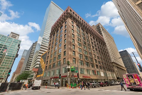 A city street with a large building in the middle of the frame.