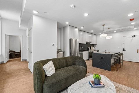 A living room with a grey couch and a coffee table with a plant on it.