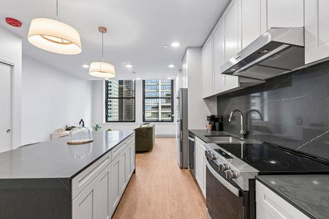 A modern kitchen with a long counter and a stove top oven.