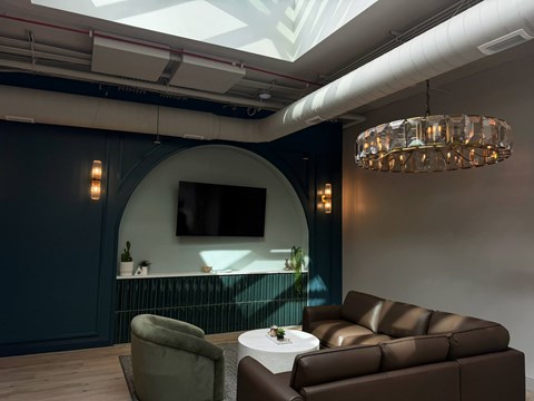 A modern living room with a brown leather sofa and a glass chandelier.