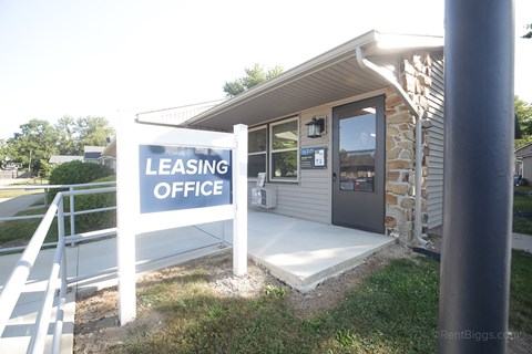 A leasing office is located in a small building with a stone wall.