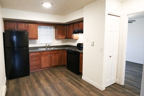 A kitchen with black appliances and wooden cabinets.