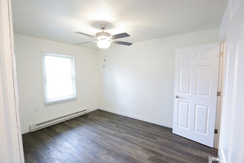 A room with a ceiling fan and a door.