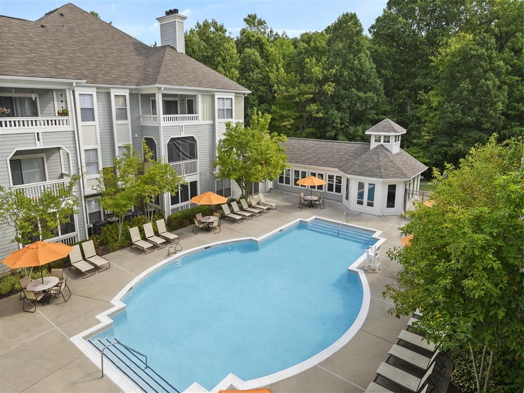 an aerial view of a swimming pool with umbrellas in front of a hotel