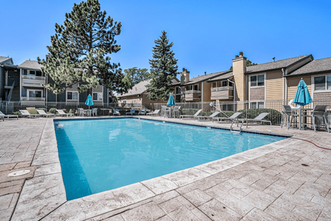 A swimming pool surrounded by a patio and chairs.
