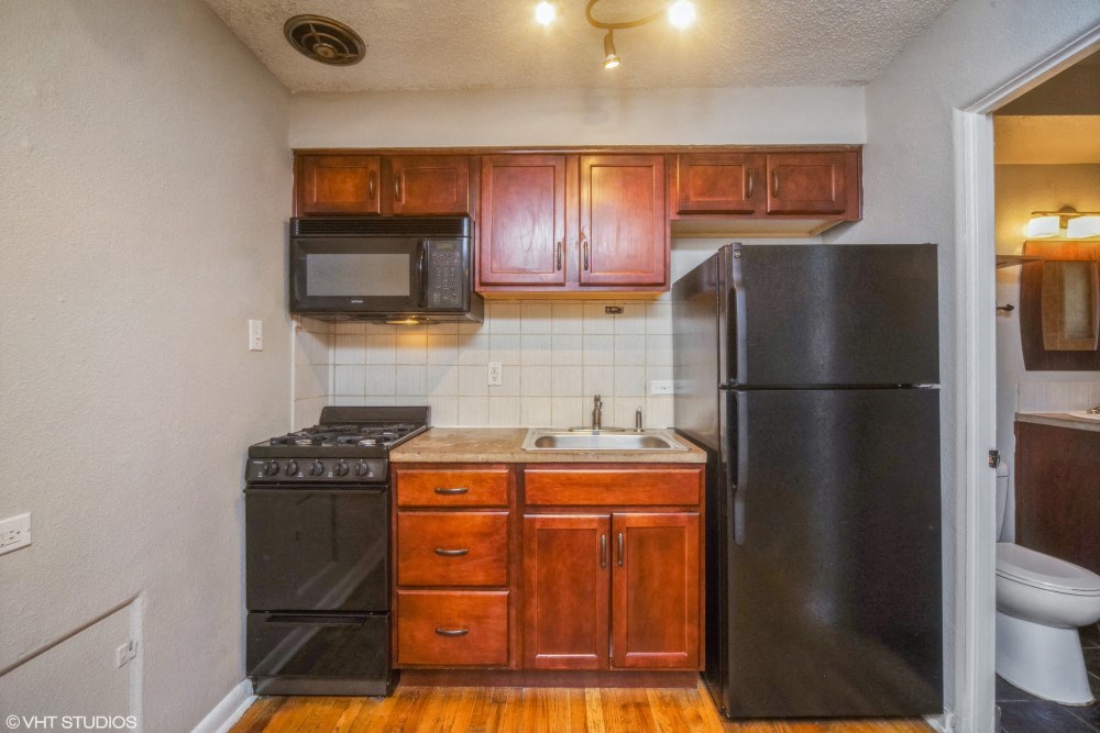 Rich wood cabinetry and tiled backsplash in the kitchen at 1355 Pearl in Denver, CO