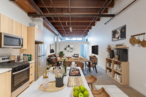 A kitchen with a wooden table and chairs, a refrigerator, a stove, a microwave, and a TV.