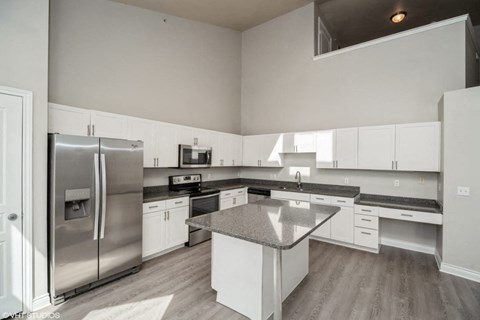 a large kitchen with stainless steel appliances and white cabinets