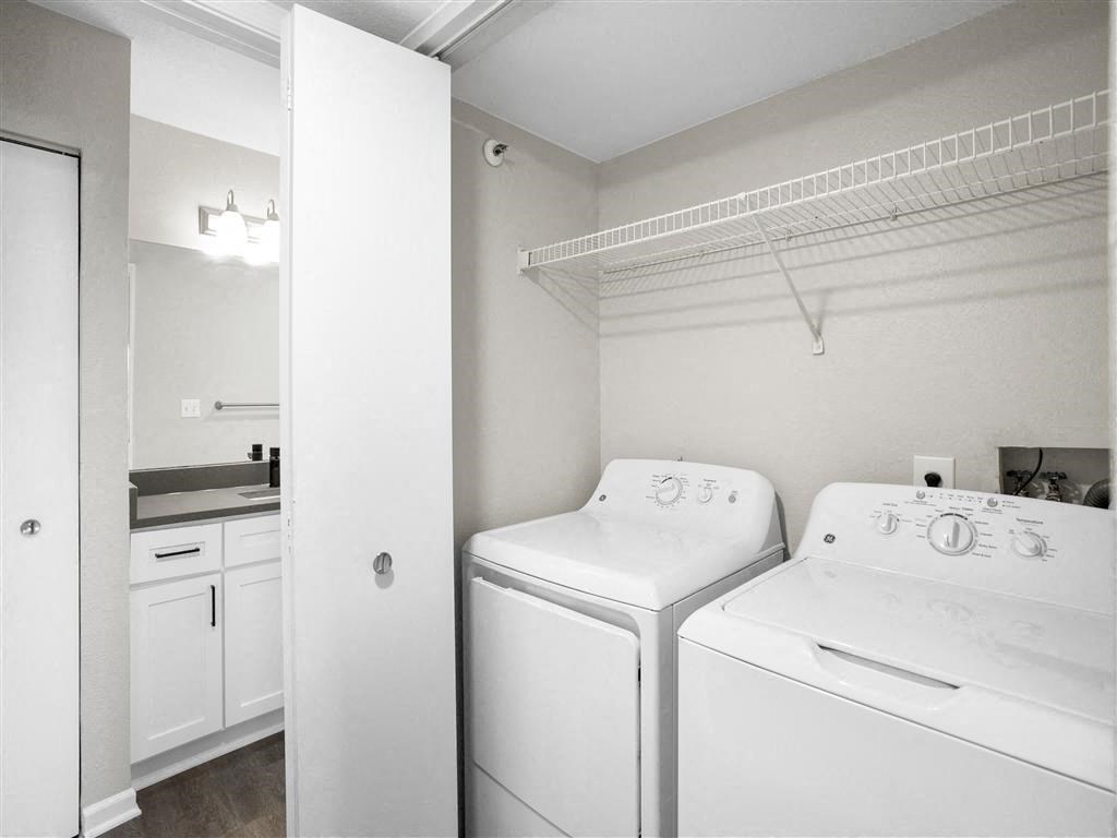 a white laundry room with two washes and a dryer