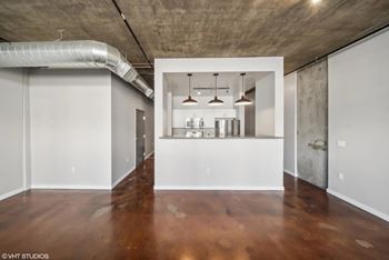 a living room with white walls and a kitchen in the distance