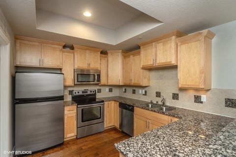 a kitchen with granite counter tops and wooden cabinets