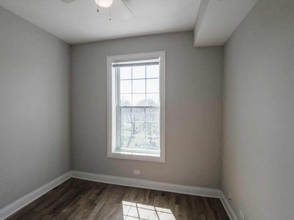 Bedroom one with neutral paint color and wood floors