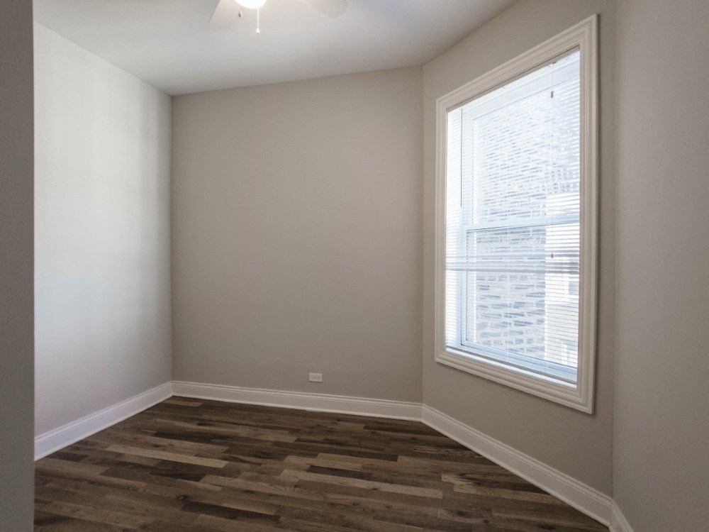 Bedroom two with rich wood flooring and neutral paint color