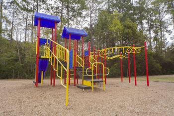 A playground with a yellow and red slide and a blue canopy.