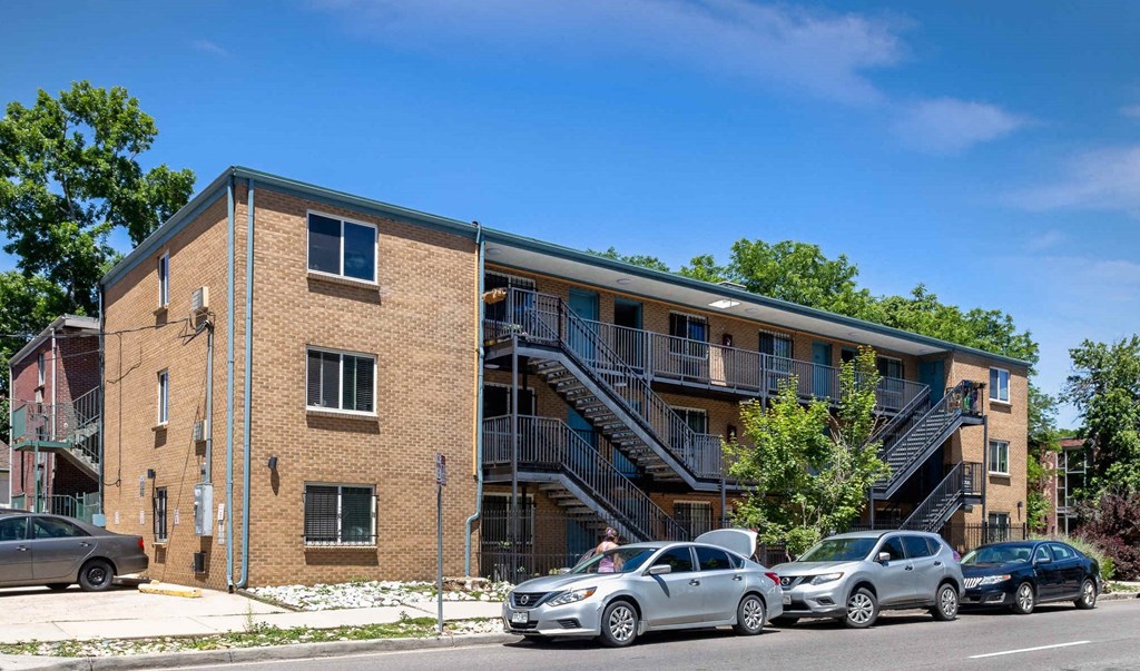 a brick apartment building with cars parked in front