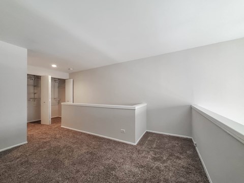 a bedroom with white walls and carpet and a closet