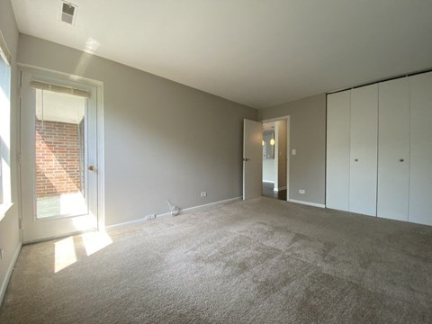 a living room with carpet and a door into a bedroom