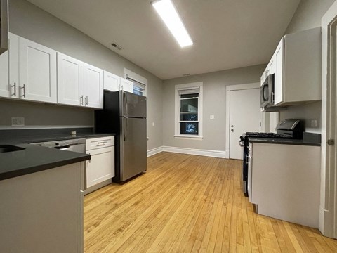 A kitchen with wooden floors and black countertops.