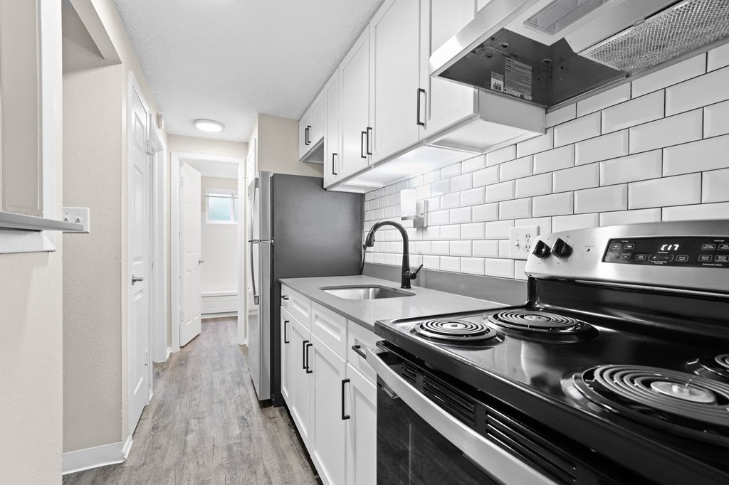 a kitchen with white cabinets and black appliances