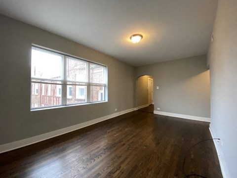a living room with a large window and wooden floors