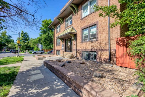 A red brick house with a grey sidewalk in front 1170 N Logan St in Denver, CO