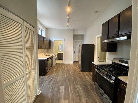 A kitchen with black appliances and wooden floors.