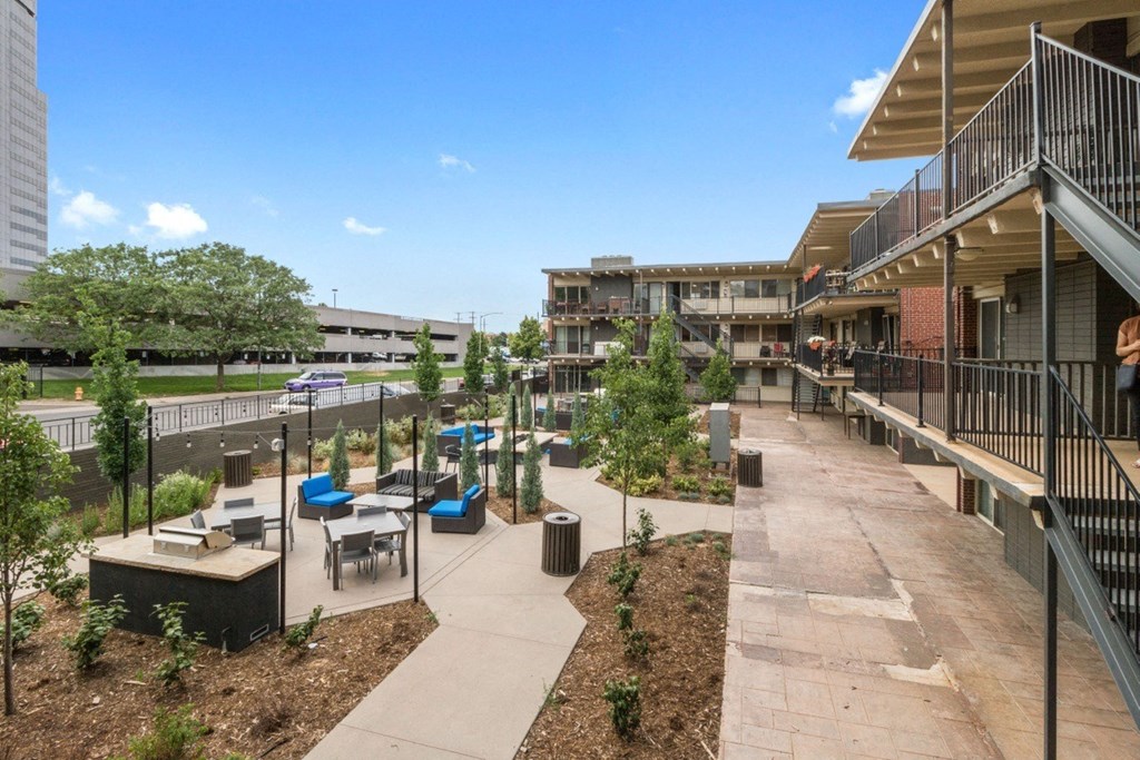 a courtyard with tables and benches and buildings in the background