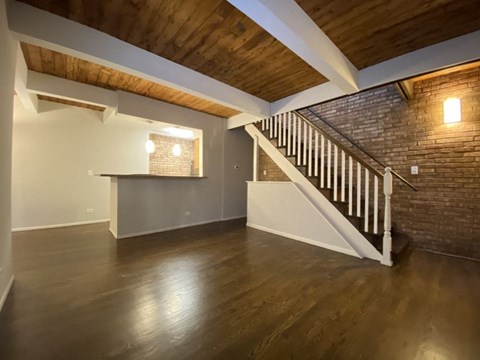 a living room with a staircase and a brick wall