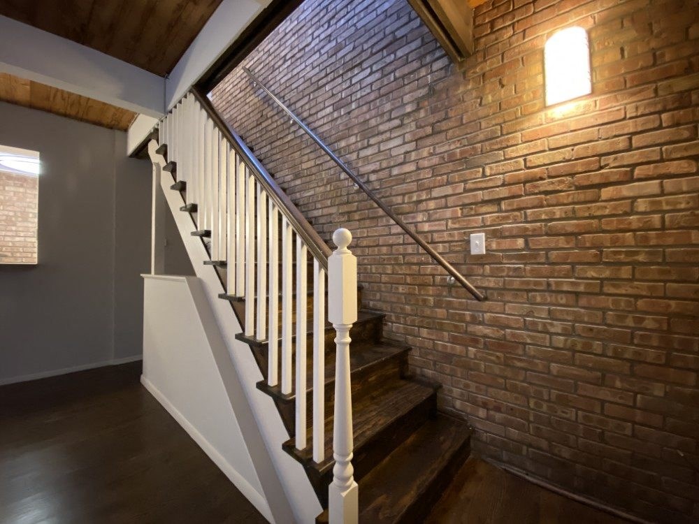 Staircase with exposed brick wall