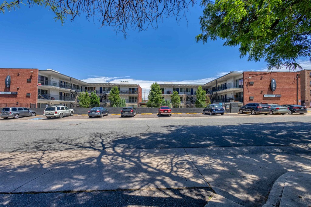 a street view of an apartment complex with cars parked on the street