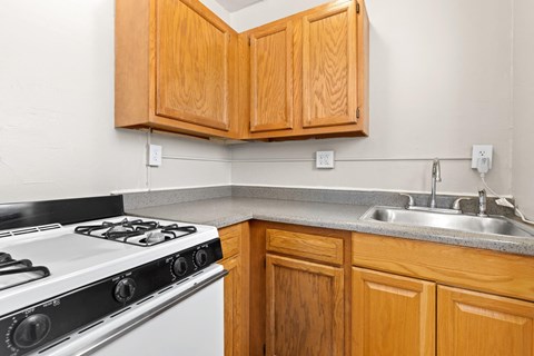 A kitchen with a white stove and wooden cabinets 1170 N Logan St in Denver, CO