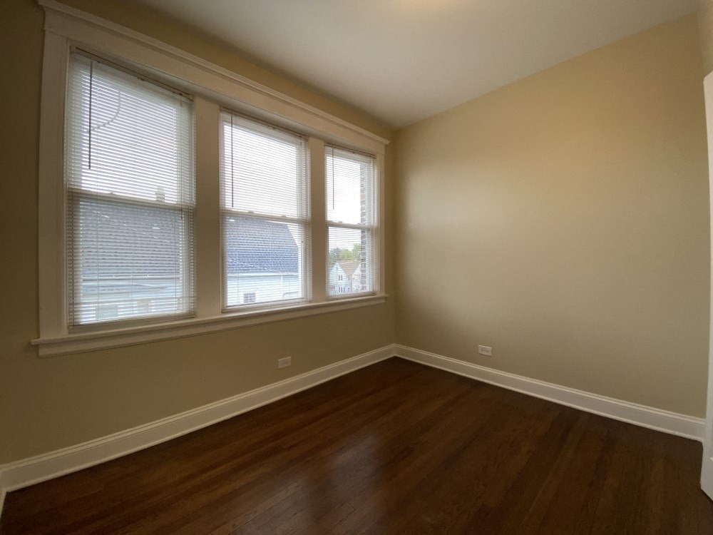 A room with wooden floors and two windows.