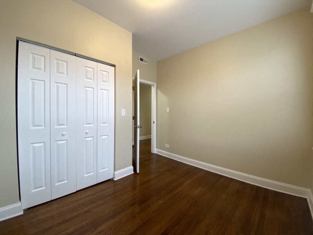A white door is in a room with wood floors and white walls.