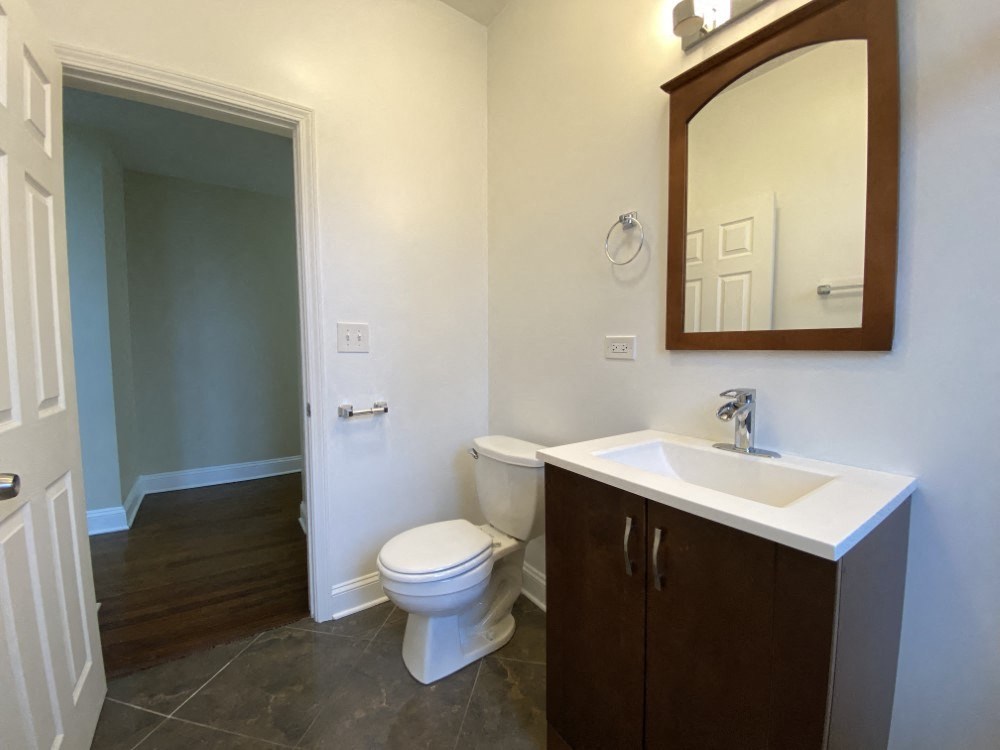 A bathroom with a toilet, sink, and mirror.