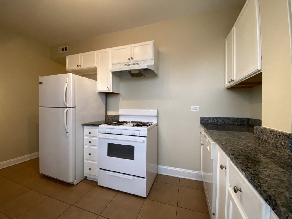 A kitchen with white appliances and granite countertops.