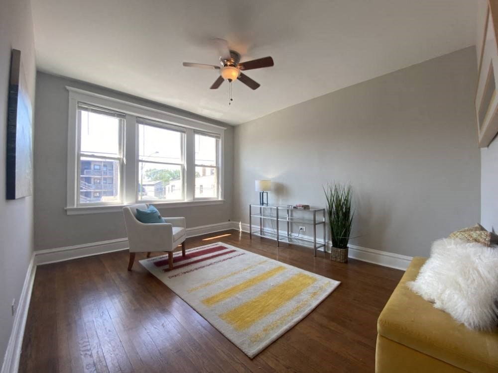A room with a ceiling fan and a yellow rug.