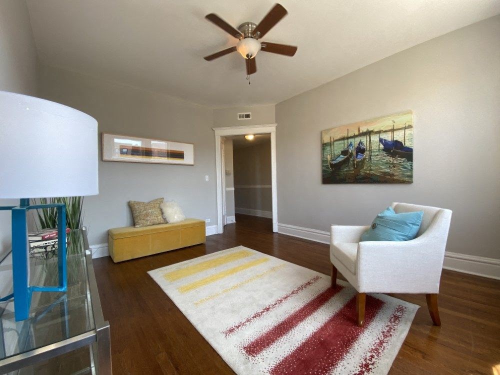 A living room with a white chair and a rug.
