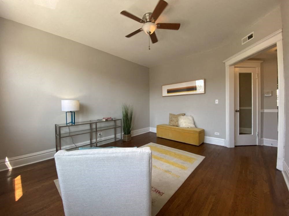 A living room with a white chair and a yellow bench.