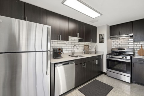 A modern kitchen with a stainless steel refrigerator and black cabinets.