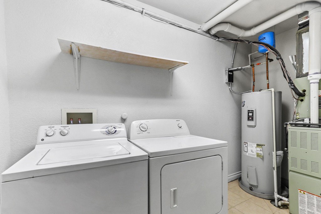 a washer and dryer in a laundry room with a boiler and a refrigerator