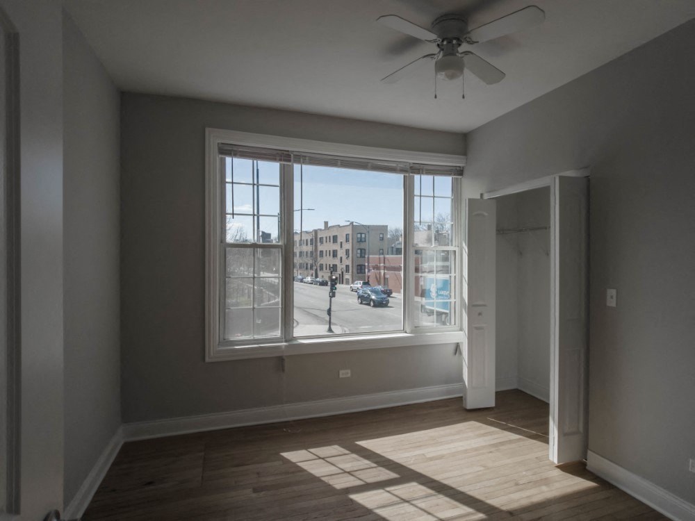 Bedroom two with large windows and a ceiling fan