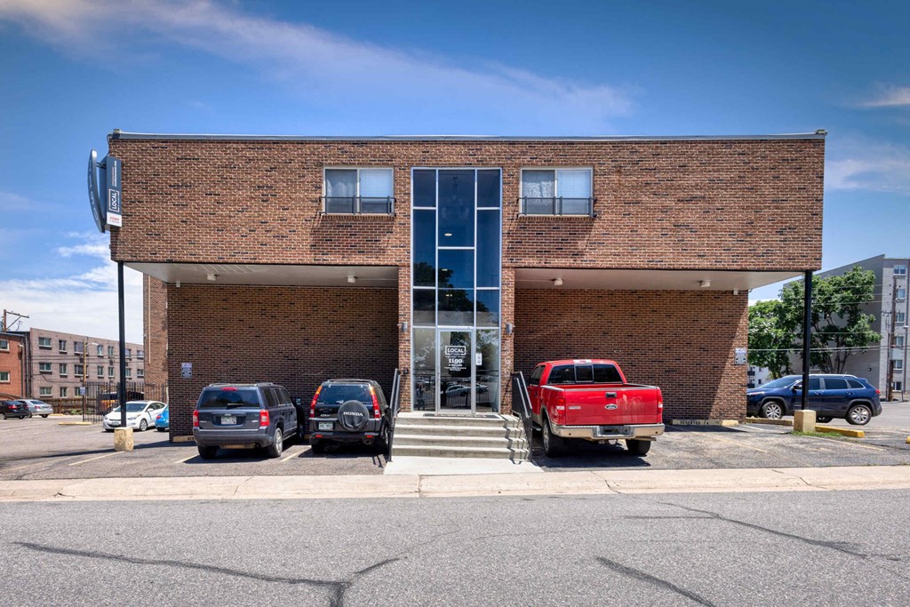 the front of a brick building with cars parked in front